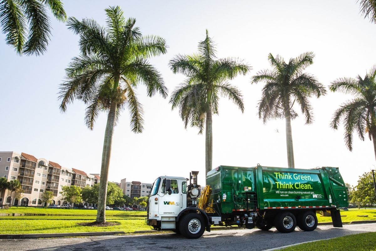A WM garbage truck passes up a row of palm trees on its commercial trash pickup route in Brandon, Florida..