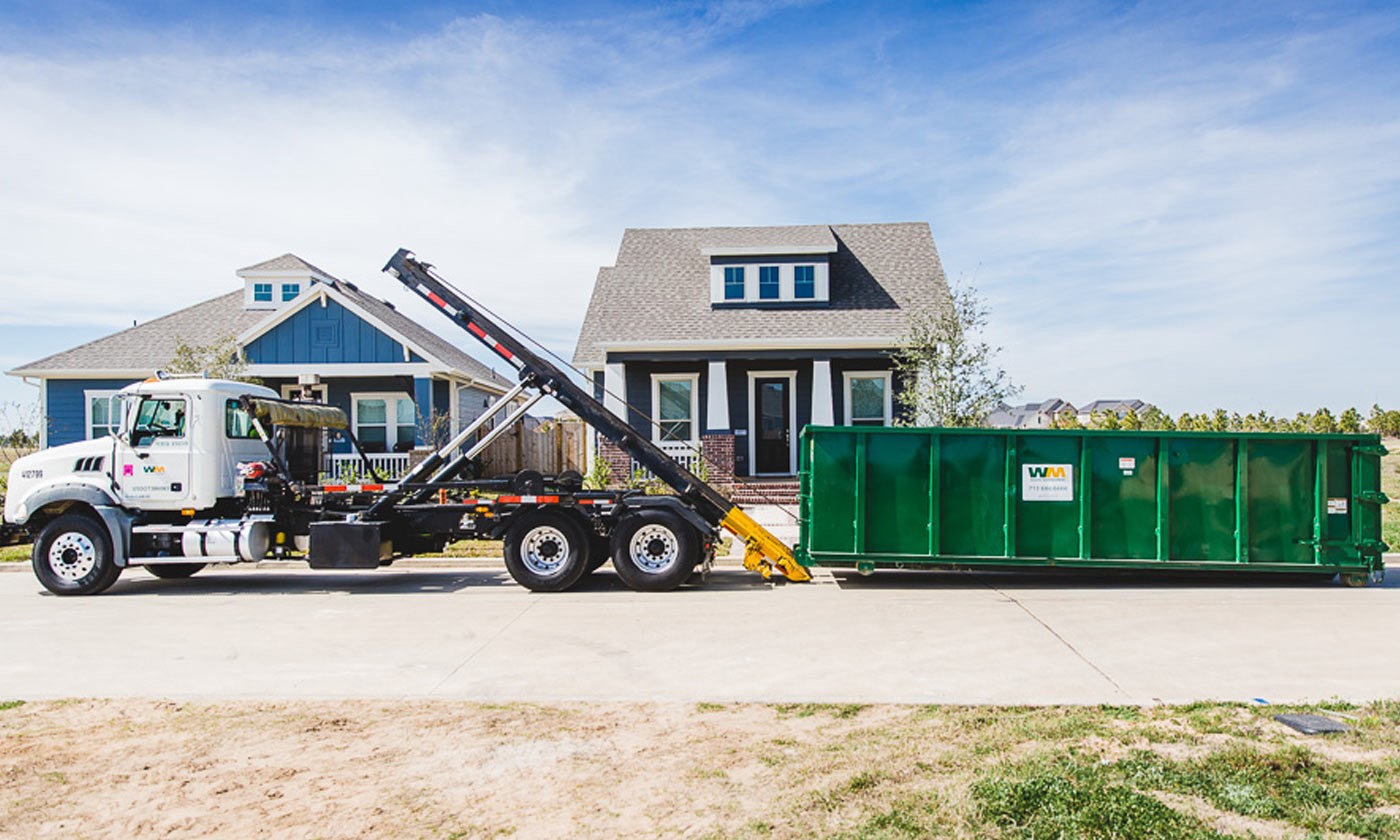 A temporary roll-off dumpster being unloaded from a WM truck.