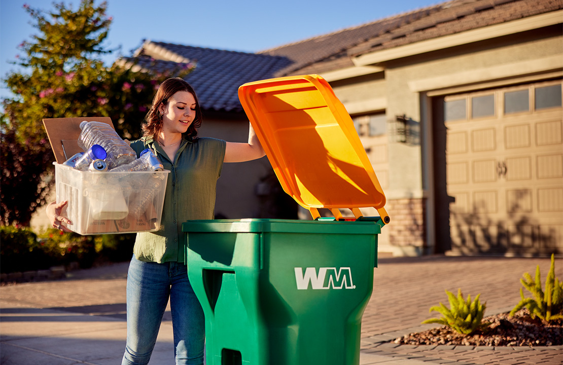 WM customer empties recyclables into WM curbside residential recycling container.